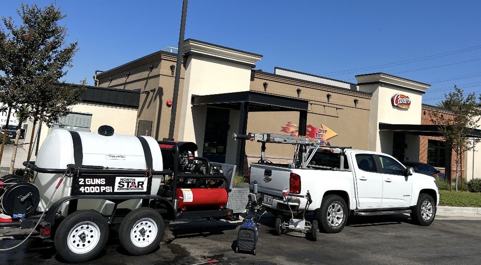 Power washing contractor truck and hot-water trailer rig on site at a commercial restaurant property