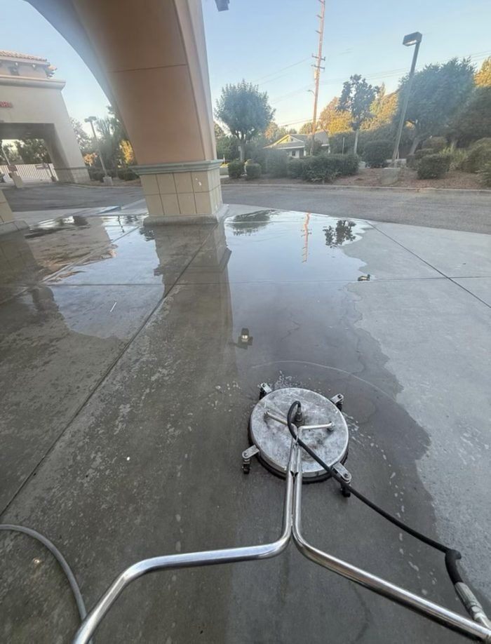 Drive-up canopy concrete during cleaning β the contrast line showing removed traffic film