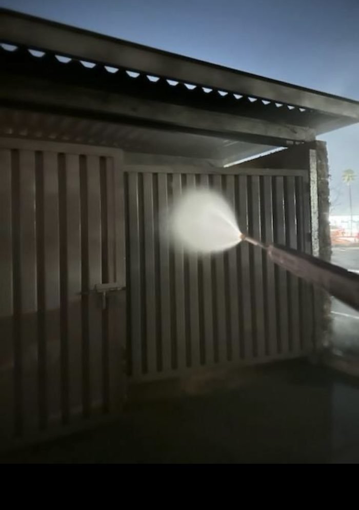 Hot-water washdown of a dumpster enclosure gate and louvers