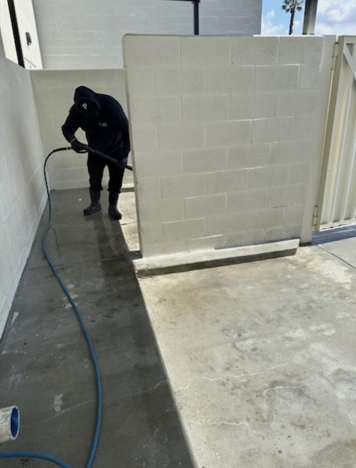 Technician detailing an enclosure interior β walls and corners after the slab wash