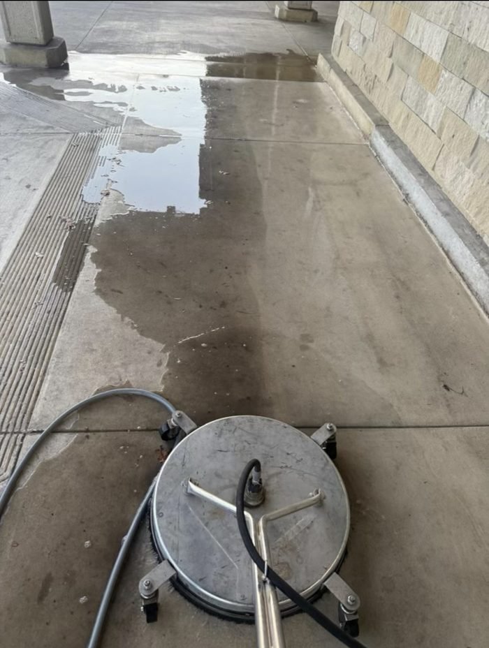 Covered entry walkway mid-service β cleaned concrete meeting the still-soiled section ahead of the machine