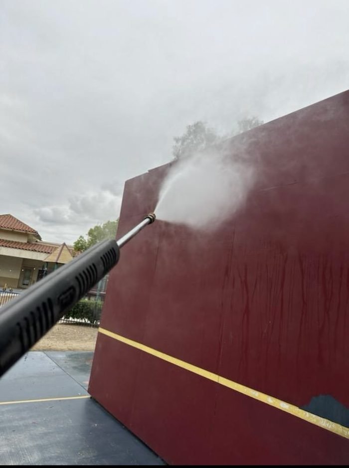 Wand-washing a playground rebound wall at a campus recreation area