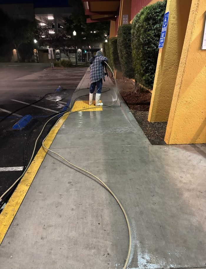 Technician wand-washing the storefront walkway along the accessibility path