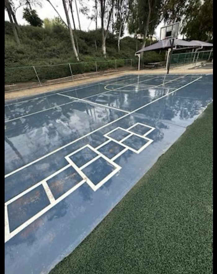 Sport court washed clean — hopscotch and basketball surfaces at a community recreation area