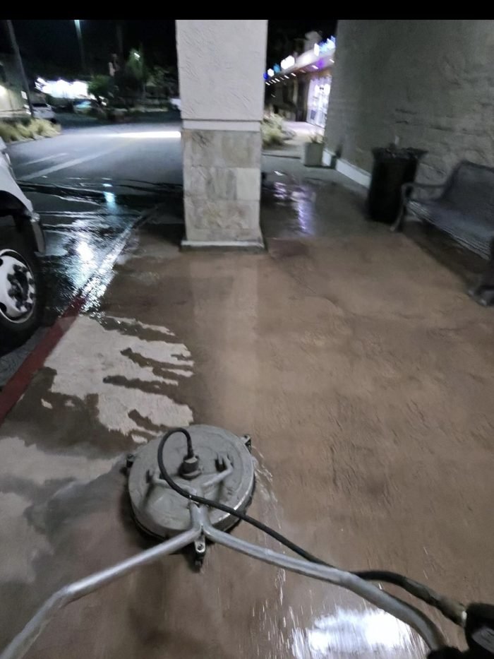 Storefront walkway mid-service β cleaned decorative concrete against the traffic-film buildup