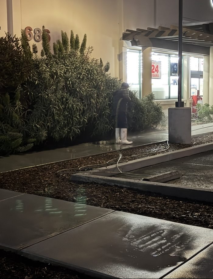 Storefront and planting-line washdown at a 24-hour retail property